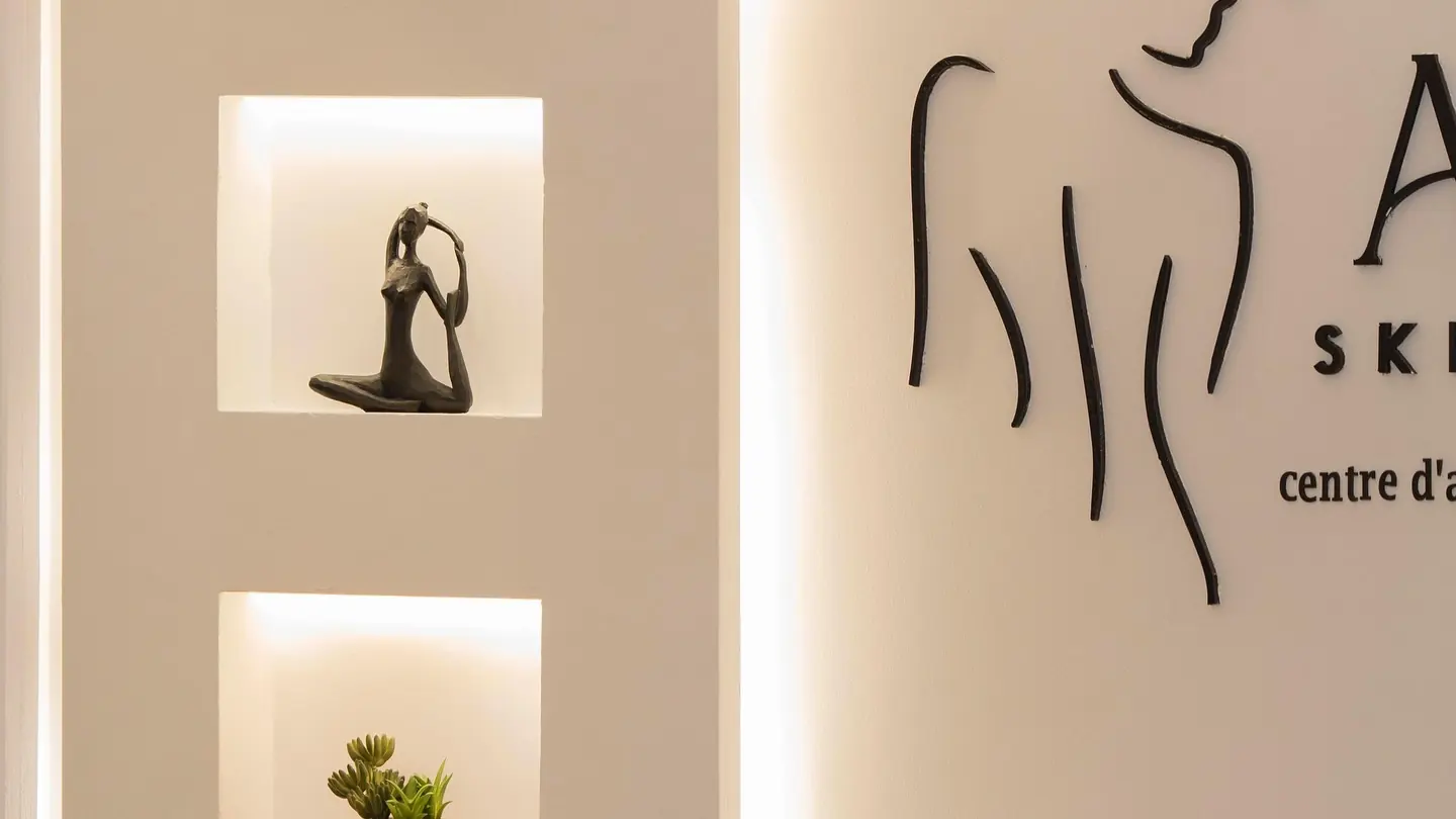 Les niches éclairées de l'accueil et le logo Aura Skin & Body au mur